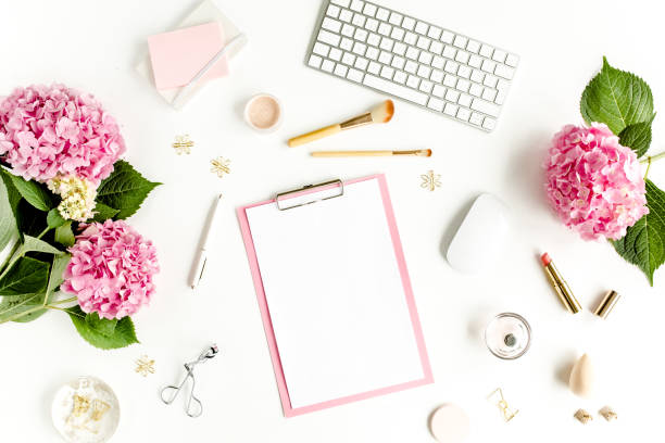istock Stylized women's desk. Workspace with clipboard, computer, bouquet hydrangea, accessories on white background. Flat lay. Top view 1270682066