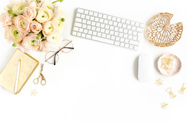 istock Stylized women's home office desk. Workspace with computer, bouquet ranunculus and roses, clipboard on white background. Flat lay. Top view 1270682123