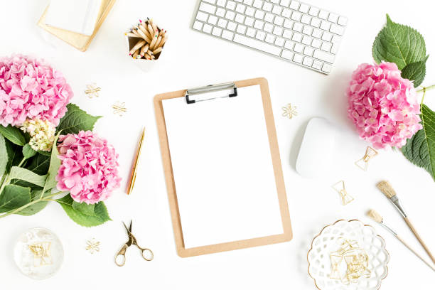 istock Stylized women's desk. Workspace with clipboard, computer, bouquet hydrangea, accessories on white background. Flat lay. Top view 1270682272