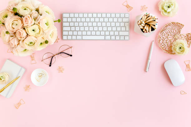 istock Stylized, pink women's home office desk. Workspace with computer, bouquet ranunculus and roses, clipboard on pink background. Flat lay. Top view 1270682978