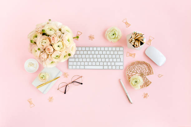istock Stylized, pink women's home office desk. Workspace with computer, bouquet ranunculus and roses, clipboard on pink background. Flat lay. Top view 1270683248