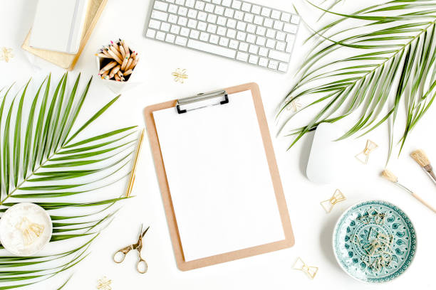 istock Flat lay home office desk. Female workspace with computer, clipboard, tropical palm leaves, accessories on white background. Top view 1270683295
