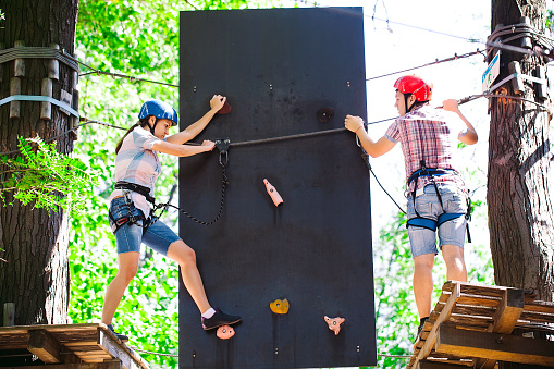 adventure climbing high wire park - people on course in mountain helmet and safety equipment.