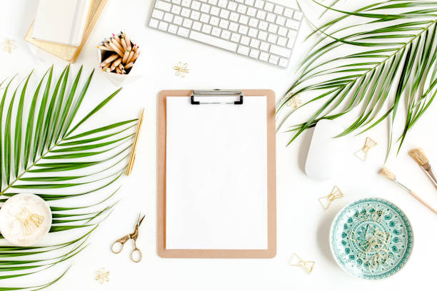 istock Flat lay home office desk. Female workspace with computer, clipboard, tropical palm leaves, accessories on white background. Top view 1270683657
