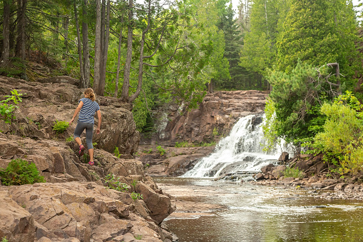 Rear view of a girl walking up the rocks near waterfalls at Gooseberry Falls Sate Park.