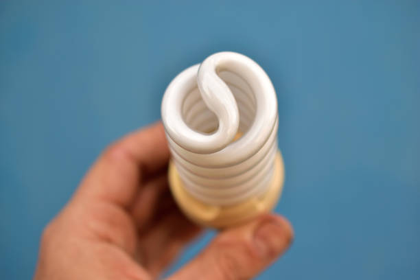 A compact fluorescent light bulb emits a soft blue glow, showcasing its unique swirl design. The lighting creates an artistic ambiance, enhancing the overall atmosphere in the room.