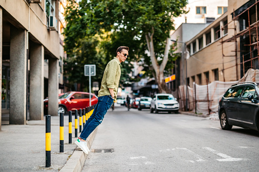 Young Caucasian man standing on sidewalk edge.