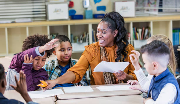 istock Elementary school teacher handing out paper to students 1270685706