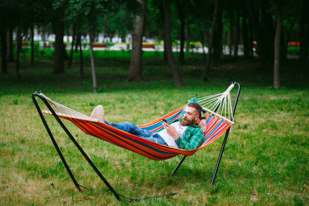 istock man using an app on his mobile phone white swinging in a hammock. 1270685895
