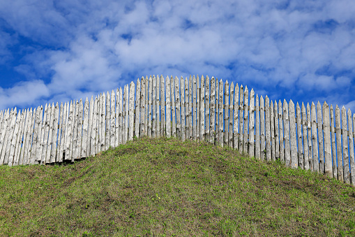 Sharp protective palisade on the earthen rampart of the old fortress