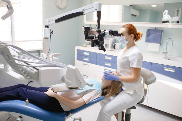 istock Female dentist with dental tools - microscope, mirror and probe treating patient. Medicine, dentistry and health care concept. 1270689669