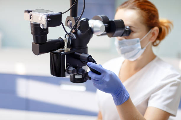 istock Female dentist with dental tools - microscope, mirror and probe treating patient. Medicine, dentistry and health care concept. 1270689684