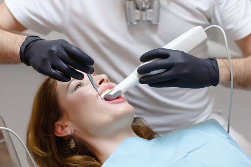 El dentista escanea los dientes del paciente con un escáner 3d photo
