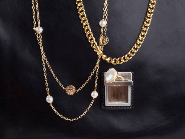 istock Two women`s gold necklaces on male black leather case 1270693562