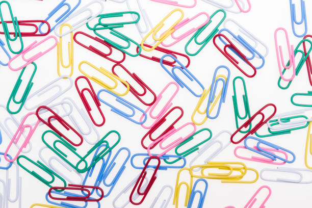 Scattered paper clips on a white background. Office accessories.
