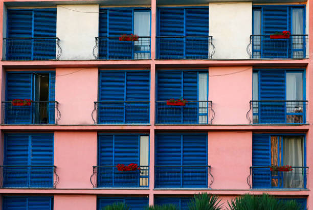 istock Balconies, flower decorations and windows with closed and open blue shutters in an apartment building. 1270696790