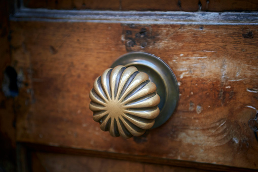 Italian antique retro vintage door knob at the wooden front door. Element of the classic Italian design and architecture