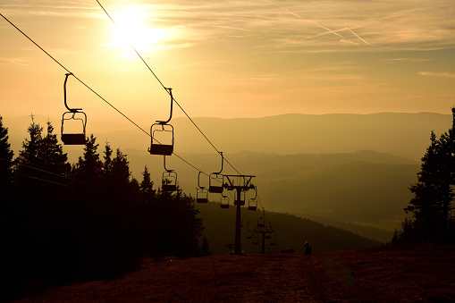 Ski chair lift cable car in the mountains at orange sunrise