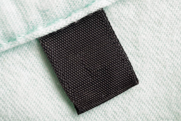 istock Black blank laundry care clothes label on cotton shirt background 1270707377