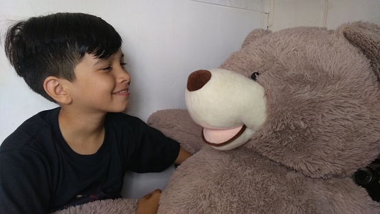 Cuteness Wins.  A handsome young child from the Philippines enjoys some quality time with a Monster Size Teddy Bear.  Fun and Good Times roll, and love is shared everywhere.  Cuteness Wins.