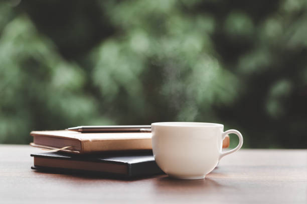 istock Hot coffee, smoke, with books and pens for note taking with beautiful nature background. 1270726077