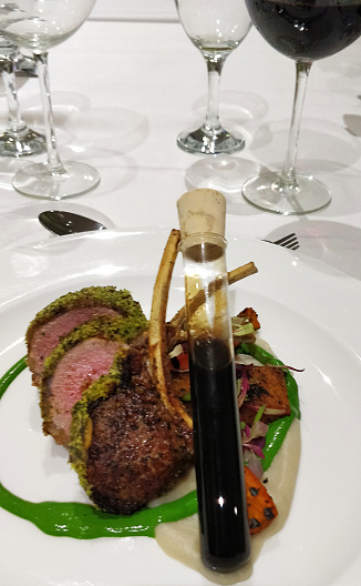 Shot of a rack of lamb served a test tube filled with sauce at a one dining restaurant