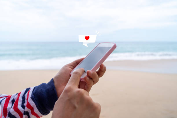 istock Heart sign on chat box icon on smartphone at summer beach technology concept. 1270732629
