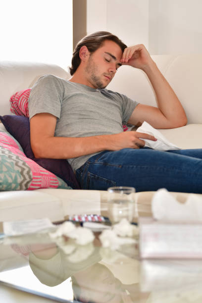 istock Handsome young man taking a nap and holding a napkin while lying on a sofa. Relaxation and rest concept. 1270734156