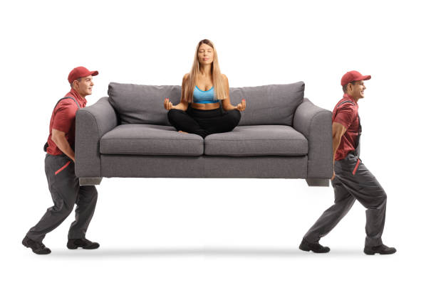 istock Two movers carrying a sofa with a young woman practicing yoga 1270741250