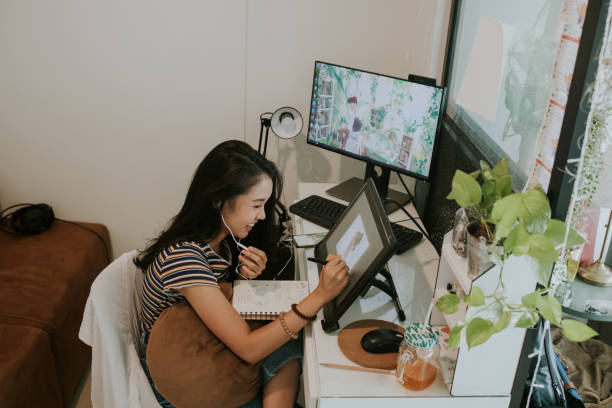 Cartoonist woman with good feeling create good design work-stock photo Thai young animator creator discussing her work with client in the smartphone while sketching her cartoon character at her small office space, Bangkok Thailand young graphic designer stock pictures, royalty-free photos & images