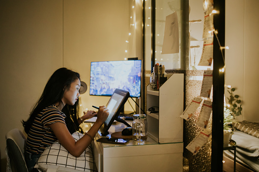 The concentration of Thai graphic designer and creative animator girl is spending time on her work in the nighttime at home, Bangkok Thailand