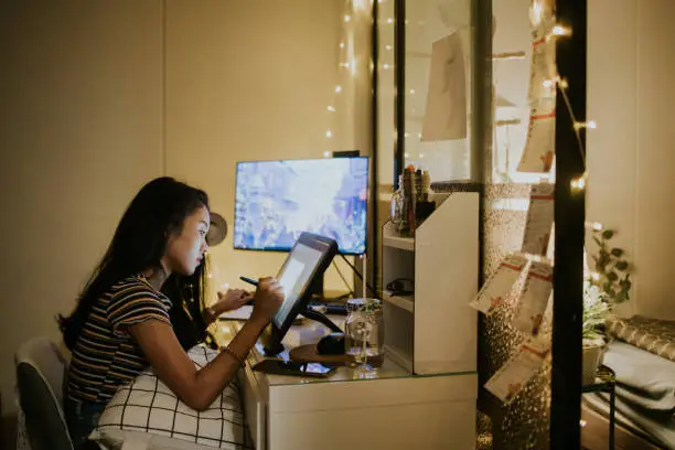 The concentration of Thai graphic designer and creative animator girl is spending time on her work in the nighttime at home, Bangkok Thailand