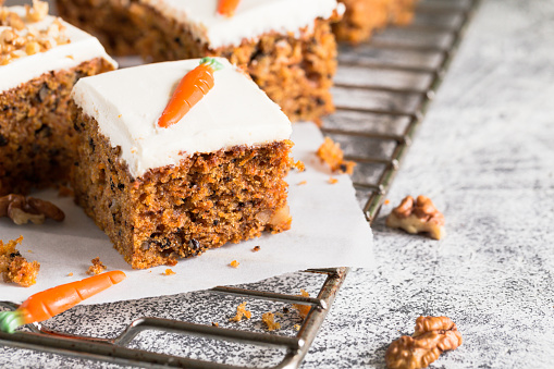 pieces of carrot cake with walnuts with icing cream on a light background. tinting. selective focus/