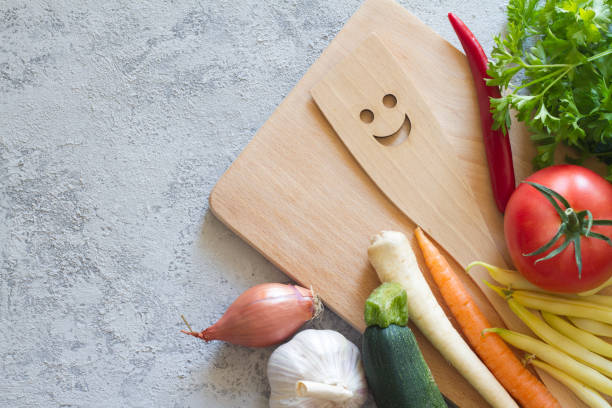 istock Vegetables, cutting board and smiling spoon on concrete background 1270744767