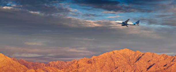 istock Jet passenger airplane above mountains at sunset 1270747606