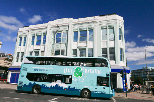 A bus with Brighton & Hove Live & Breathe Campaign in East Sussex, England, and people in the background. The building is the Royal Bank of Scotland.