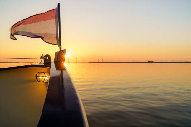 Fore-deck steel boat with Dutch flag during sunset cruise