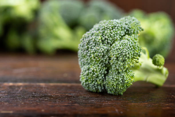 Inflorescences of fresh broccoli on a wooden background. Inflorescences of fresh broccoli on a wooden background. Fiber-rich food. broccoli crowns stock pictures, royalty-free photos & images