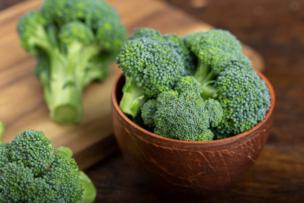 Bunch of fresh green broccoli Bunch of fresh green broccoli on clay plate over wooden background. broccoli crowns stock pictures, royalty-free photos & images