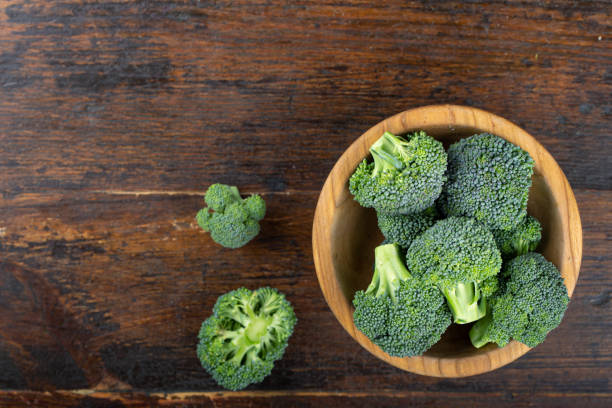 Fresh broccoli with in bowl on wooden table close up. Fresh broccoli with in bowl on wooden table close up. Fiber-rich food. broccoli crowns stock pictures, royalty-free photos & images