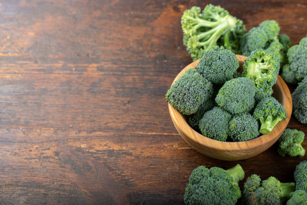 Fresh broccoli with in bowl on wooden table close up. Fresh broccoli with in bowl on wooden table close up. Fiber-rich food. broccoli crowns stock pictures, royalty-free photos & images