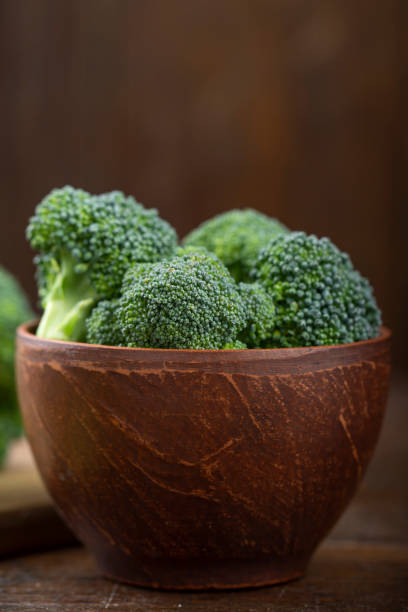 Bunch of fresh green broccoli Bunch of fresh green broccoli on clay plate over wooden background. broccoli crowns stock pictures, royalty-free photos & images