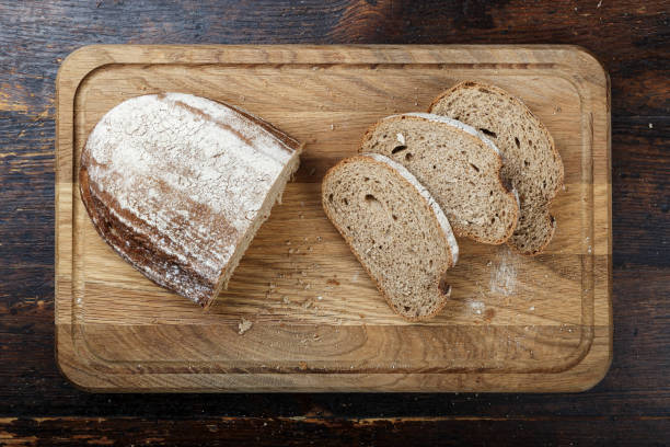 нарезанный свежий ржаной хлеб на коричневом деревянном фоне. - country bread стоковые фото и изображения