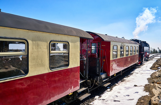 Steam locomotive with passenger wagons in winter on the Brocken in the Harz Mountains with snow. Germany