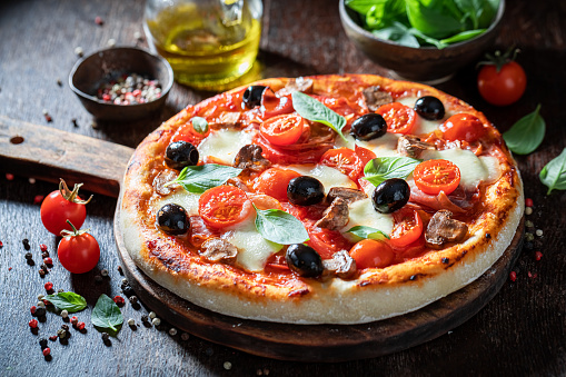 Delicious pizza Capricciosa with mozzarella, prosciutto and tomatoes on wooden table