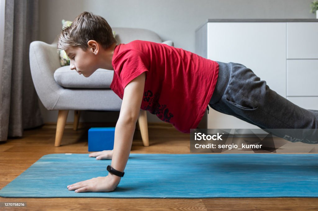 Small Boy On Yoga Mat At Home Holding Plank Pose Stock Photo