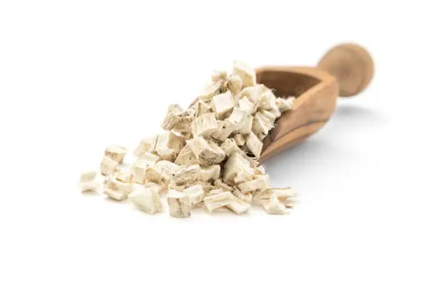 Marshmallow root (Althaea officinalis) in wooden scoop on white background