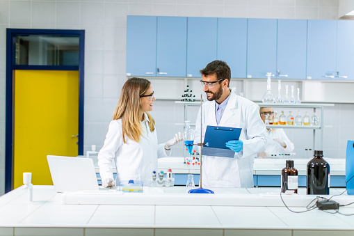 Researchers working with blue liquid at separatory funnel in the laboratory