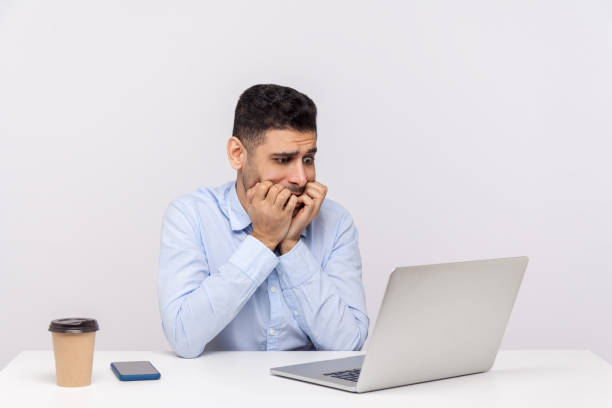 istock Nervous scared man employee sitting office workplace, looking worried anxious at laptop screen and biting nails 1270761923