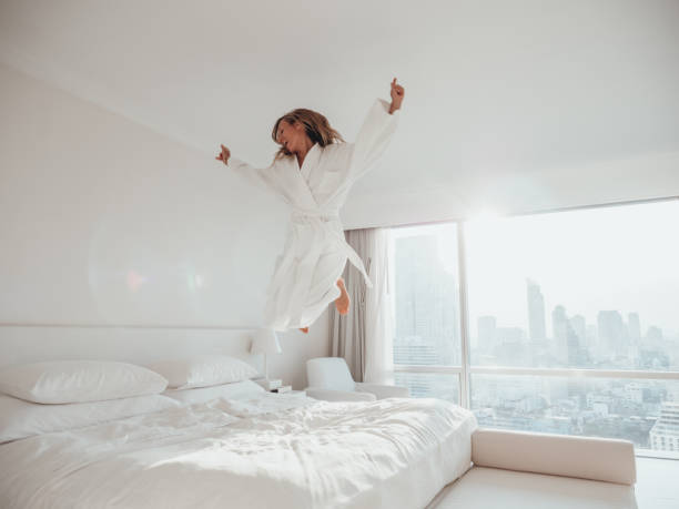istock Woman jumping on bed in hotel room 1270763697